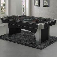 a black pool table sitting on top of a carpeted floor next to a window