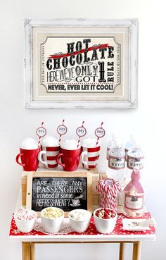 a red and white table topped with cups filled with hot chocolate next to a sign