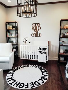 a baby's room with a white crib, black and white rug, and wooden floors