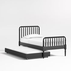 a black and white bed sitting next to a footstool on a white floor