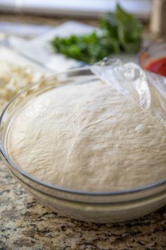 a bowl filled with dough sitting on top of a counter next to other food items