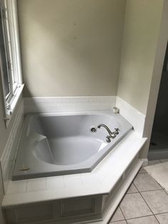 a bathtub in a bathroom with tile flooring and white tiles on the walls