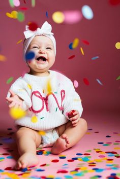 a baby sitting on the floor surrounded by confetti