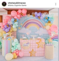 a birthday party with balloons, stars and rainbows on the wall in front of it