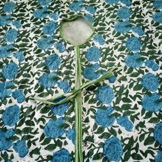 a white and blue flower with green stems on a floral print tablecloth that looks like it has been cut in half