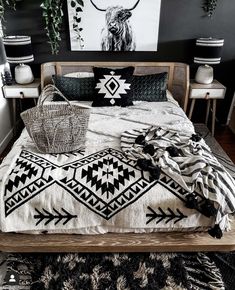 a bed with black and white blankets, pillows and pictures on the wall behind it