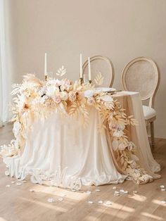 a table with flowers and candles on it in the middle of a room next to two chairs