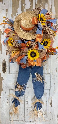 a scarecrow with sunflowers and straw hat hanging on a door