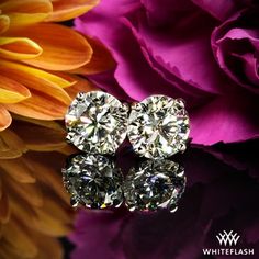 two diamond studs sitting on top of a purple and yellow flower next to flowers