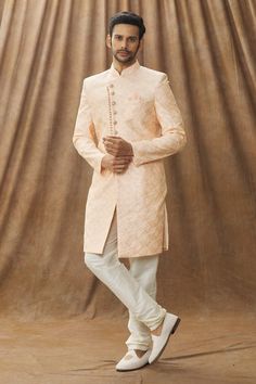 Peach sherwani with floral embroidery. Paired with cream churidar.
Component: 2
Pattern: Embroidered
Type Of Work: Floral
Neckline: Mandarin Collar
Sleeve Type: Full
Fabric: Sherwani: Art silk, Churidar: Dupion art silk, Lining: Faux satin
Color: Peach
Other Details: 
Note: The pocket square worn by the model is not for sale
Occasion: Wedding - Aza Fashions Orange Zari Work Sherwani For Wedding, Orange Sherwani With Zari Work For Wedding, Orange Wedding Sherwani With Zari Work, Wedding Orange Sherwani With Zari Work, Orange Sherwani For Wedding Eid Festival, Orange Sherwani For Wedding And Eid, Orange Sherwani For Wedding At Eid, Peach Long Sleeve Kurta For Wedding, Peach Kurta With Zari Work For Wedding