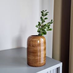 a wooden vase sitting on top of a white table next to a window sill