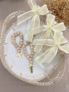 a white plate topped with wooden beads and cross necklaces next to a vase filled with flowers