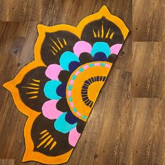 a colorful rug on the floor with an intricate design in yellow, blue, pink and black