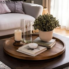 a coffee table with books, candles and a potted plant on it