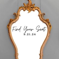 a mirror with the words find your seat written on it and an ornate frame in gold