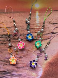 four flower earrings are on the beach with water and sunset in the backgroud