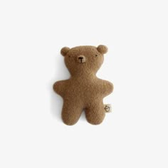 a small brown teddy bear laying on top of a white wall next to a keychain