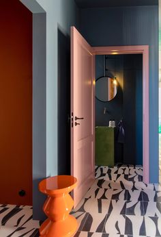 a bathroom with black and white tile flooring and colorful walls, along with an orange stool