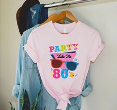 "80s Party Shirt, Party Like 80s Shirt, 80s Fan Shirt, 80s Lover Shirt, 80s Theme Party Shirt, 80s Vintage Shirt,80s Retro Shirt,80s Clothing 🎈HOW TO ORDER 1-) Please, check and review all the photos. 2-) Choose your t-shirt size and color. *Different styles of shirts may have different shades of same color choice due to different manufacturer brands. *For this reason, we recommend you to match shirts from the same styles if you want precisely matching colors (ex. Unisex, V-necks, Toddler, etc.). 3-) Click add to cart. You can go back to add more shirts. 4-)Click \"Proceed to check out\". 5-)When you check out, you can add a note to seller for any request. 🎈PRODUCT DESCRIPTION UNISEX SHIRTS * Unisex t shirt fits like a well-loved favorite, featuring a crew neck, short sleeves and designe 80 Themed Shirt, Vintage Summer Party T-shirt, 90s Style Summer Party T-shirt, Retro Pink Party Top, 90s Inspired Summer Birthday T-shirt, 90s Summer Birthday Tops, 90s Style Summer Birthday Tops, 90s Summer Tops For Birthday, 80s Fashion Women