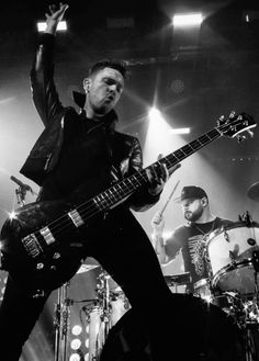 a black and white photo of a man playing the guitar on stage with his hands in the air