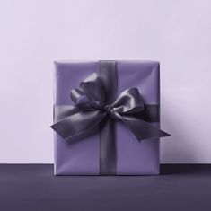 a purple gift box with a silver bow on it's side, sitting on a table