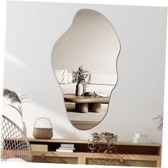 a large mirror sitting on top of a wooden dresser next to a vase and potted plant