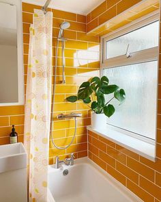 a bathroom with yellow tiles and a plant in the bathtub next to the window