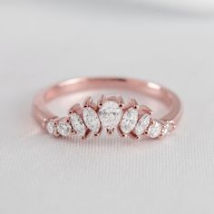 a rose gold ring with three pear shaped diamonds on the side, set against a plain white background