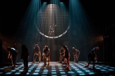 a group of people standing on top of a checkered floor in front of a spotlight