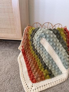 a multicolored crocheted bag sitting on the floor