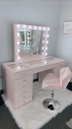 a pink vanity with lights on it and a chair