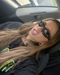 a woman wearing sunglasses is sitting in the back seat of a car