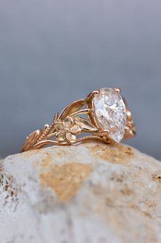 a close up of a ring on top of a rock with leaves and flowers around it