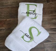 two white towels with the word family and an e on them sitting on top of a wooden floor