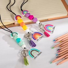 several different colored pencils and markers on a table with an open notebook in the background