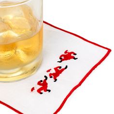 a glass filled with liquid sitting on top of a white table next to a red and black napkin