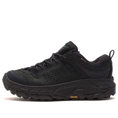 Looking for the perfect pair of shoes to take on any terrain? Look no further than the Hoka One One Tor Ultra Low GORE-TEX 'Black' 1130310-BBLC. These shoes are designed with the adventurous outdoor explorer in mind, featuring a GORE-TEX waterproof membrane to keep your feet dry in any weather. The low-cut design provides maximum stability and support, with a Vibram MegaGrip outsole for unbeatable traction on even the toughest terrains. But it's not just about function - the sleek black design o Black Low-top Rugged Trail Running Shoes, Rugged Black Low-top Trail Running Shoes, Black Rugged Breathable Sneakers, Gore-tex Low-top Walking Shoes With Vibram Sole, Low-top Gore-tex Walking Shoes With Vibram Sole, Econyl Sneakers With Round Toe For Walking, Econyl Sneakers For Walking With Round Toe, Econyl Sneakers For Walking, Rugged Black Trail Running Shoes With Vibram Sole