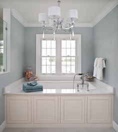 a bath room with a tub and a chandelier hanging from it's ceiling