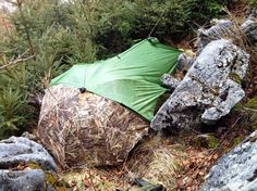 a green tent sitting on top of a rocky hillside