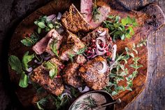 meat and vegetables on a wooden platter with dipping sauce