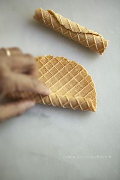 someone is holding an ice cream cone in front of the other two cones that are shaped like leaves