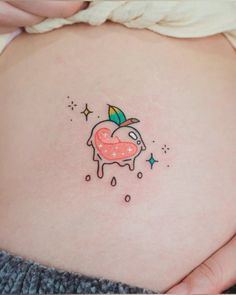 a woman's stomach with an apple tattoo on her belly and stars around it