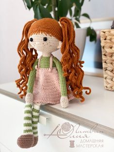 a crocheted doll sitting on top of a white table next to a potted plant