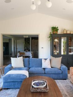 a living room with blue couches and white pillows