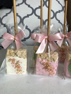 four candy bars wrapped in cellophane and tied with pink ribbon, sitting on a table