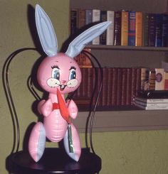 a pink stuffed rabbit sitting on top of a black table next to a bookshelf