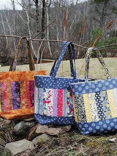 three bags sitting next to each other on top of a pile of rocks and grass