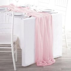 the table is set with white and pink linens, silverware and wine glasses