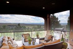 an outdoor living area with furniture and grill on the deck overlooking a golf course in the distance