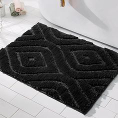 a black rug on the floor next to a bathtub in a white tiled bathroom